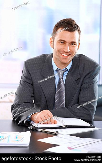 Portrait of smiling businessman sitting at table with personal organiser