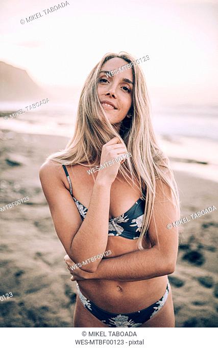Young blond woman wearing bikini at the beach and looking at camera