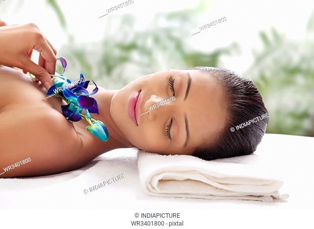 Young woman on massage table holding flower