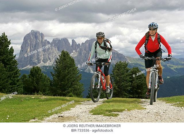 Female mountain bikers, Mts. Langkofel and Plattkofel in the background, Dolomites, Northern Italy, Europe