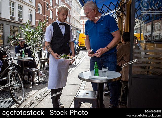 Copenhagen, Denmark, A man is served a plate by a waiter at a busy cafe on Vaernedamsvej