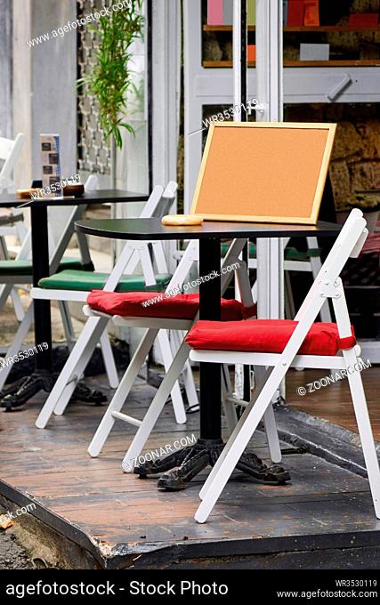 street cafe with white wooden chairs red and green pillows and black tables Istanbul