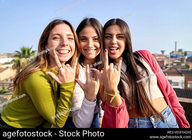 Female friends with cool attitude gesturing horn sign