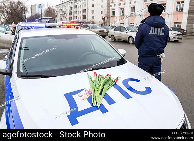 RUSSIA, YEKATERINBURG - MARCH 7, 2023: A traffic police officer has flowers to congratulate passing women drivers on 8 Marta Street ahead of International...
