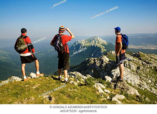 Hikers on Mount Aitzgorri (1528 m.) top and Aratz (1446 m.) mountain in background, Sierra de Aitzgorri Natural Park, Guipuzcoa, Basque Country, Spain