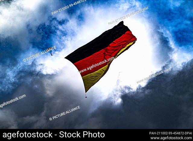 02 October 2021, North Rhine-Westphalia, Büren: Skydivers unfurl a Germany flag in the sky above Paderborn-Lippstadt Airport