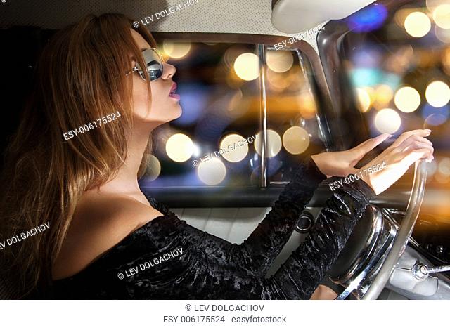 vehicle and lifestyle concept - glamorous woman in sunglasses behind the wheel in the car
