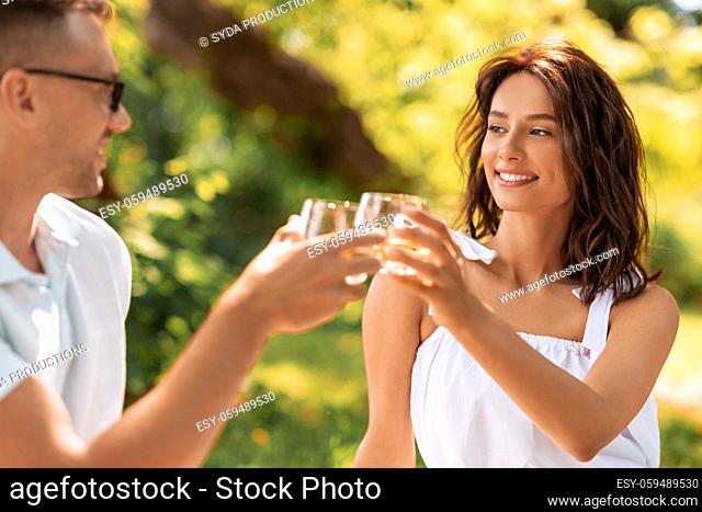 happy couple toasting drinks at summer park