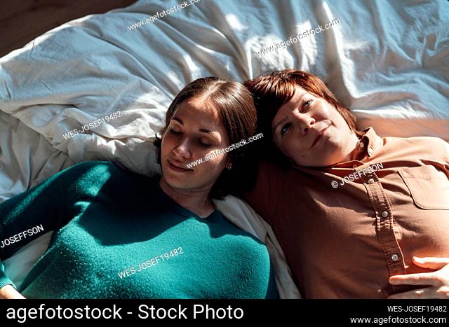 Lesbian couple resting on bed at home