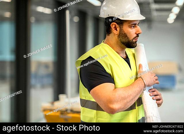 Worker holding blueprint at construction site
