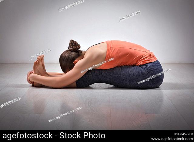 Sporty fit woman practices Ashtanga Vinyasa yoga back bending asana Paschimottanasana, seated forward bend