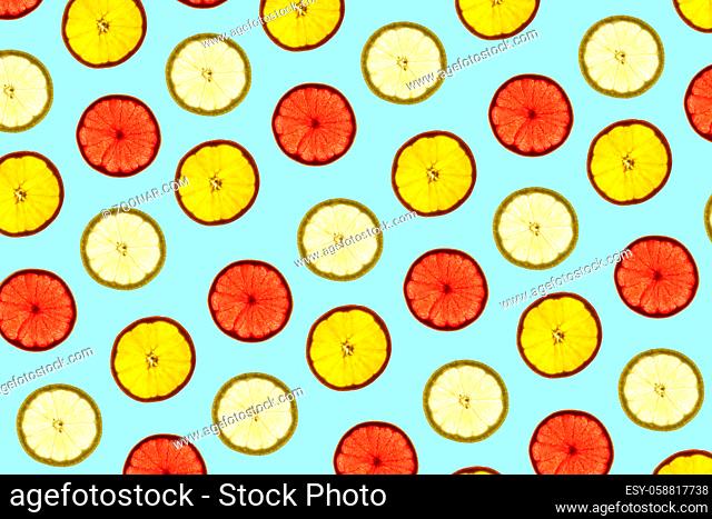 Pattern made of backlit citrus fruits slices on blue background