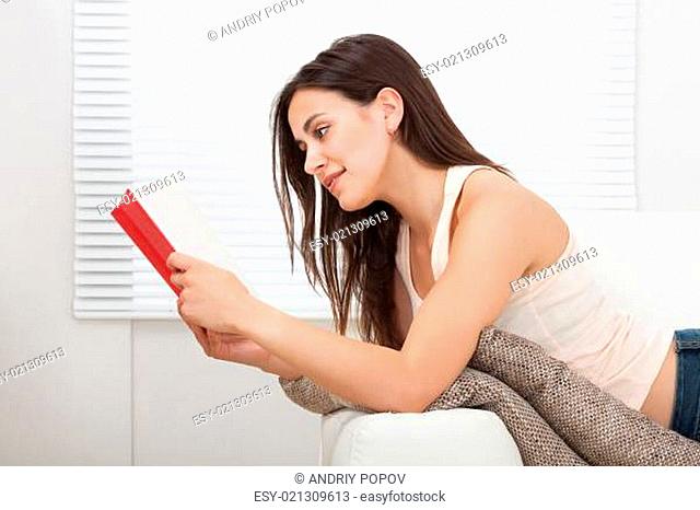 Woman Reading Book While Lying On Sofa