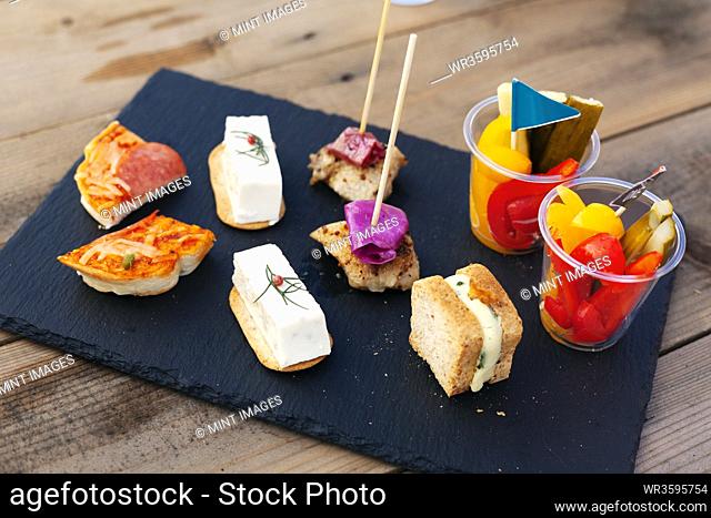 High angle close up of a selection of sandwiches and fresh vegetables on slate tray
