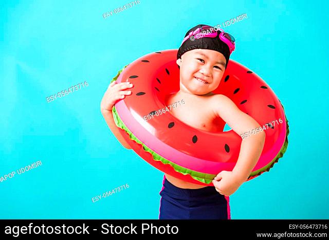 Summer vacation concept, Portrait Asian happy cute little child boy wear goggles and swimsuit hold watermelon inflatable ring, Kid having fun on summer vacation
