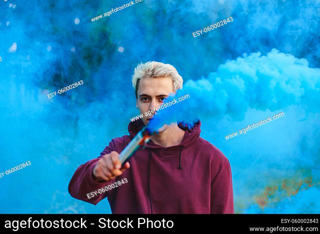 Street style man in hoodie hold hand flare with red smoke grenade bomb