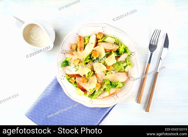 Chicken Caesar salad plate. Chicken breast, green lettuce, Parmesan cheese, and croutons, with the typical dressing, shot from the top with a place for text
