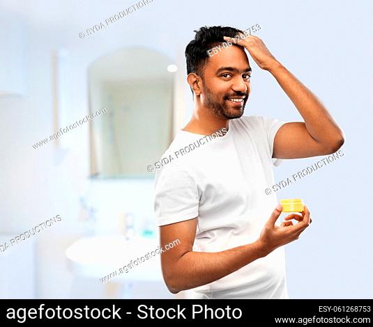 man applying hair wax or styling gel in bathroom