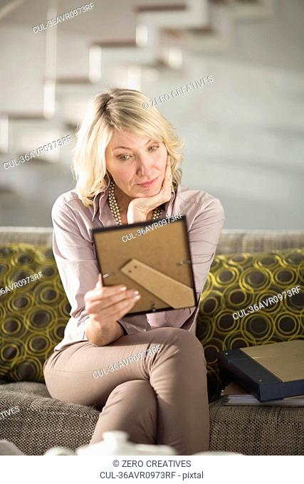 Woman admiring framed photo on couch