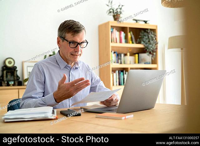 Senior businessman having an online meeting while doing home office