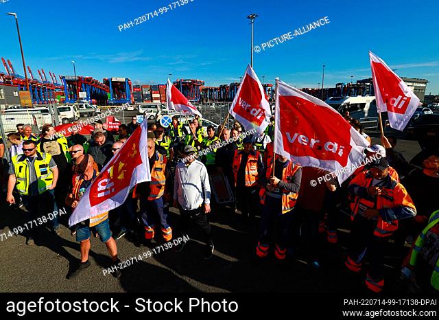 14 July 2022, Hamburg: Workers with Verdi flags protest during a warning strike in front of the Container Terminal Burchardkai (CTA) of HHLA (Hamburger Hafen...