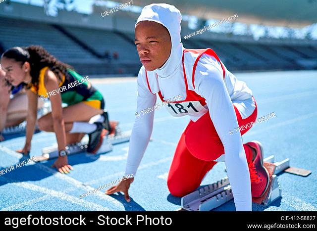 Female track and field athlete in hijab at starting block on track