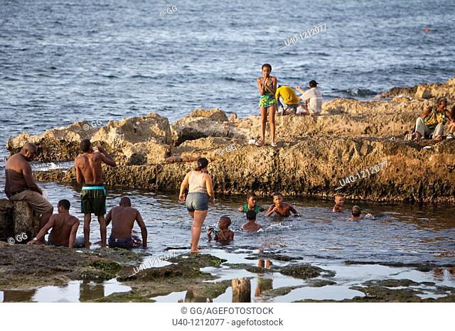 Cuba, Havana Vieja, people bathing by the Malecon at Sunset