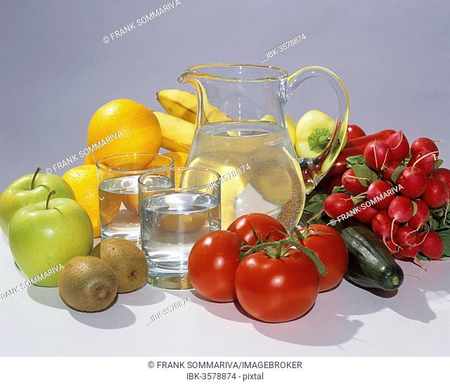 Glass carafe filled with water, two glasses, fruit and vegetables