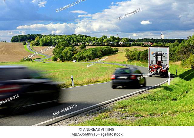 Car and truck driving on winding country road, storm clouds, motion blur, Thuringia, Germany