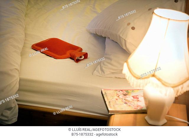 cossy atmosphere bedroom with bed, Bedside table, hot water bottle, book and lamp