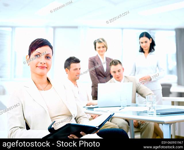 Group of five young business people working at office with businesswoman sitting in front
