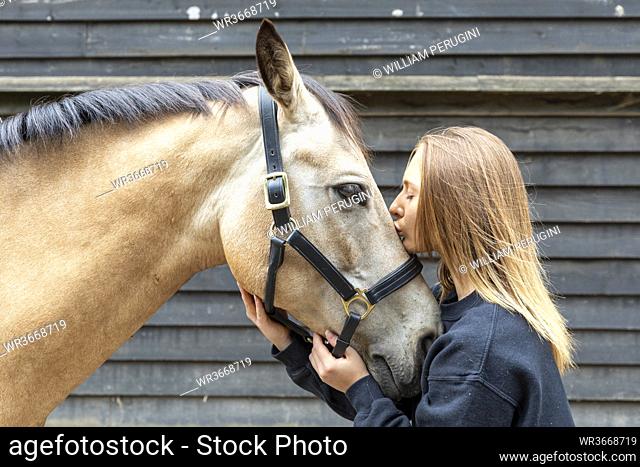 Young woman kissing her horse