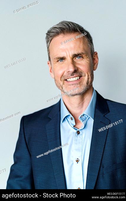 Mature businessman with blue eyes against gray background