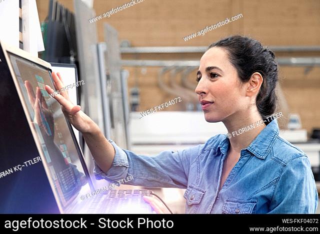 Businesswoman operating control panel screen in factory