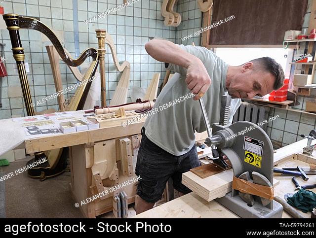 RUSSIA, ST PETERSBURG - JUNE 13, 2023: Worker Igor Novikov works on a fingerboard at the Resonance Harps musical instrument factory