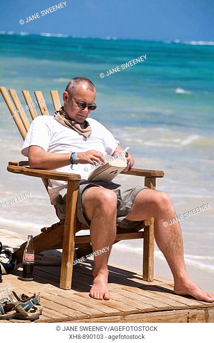 Tourist sitting in chair on beach reading book, Playa del Pablo, Little Corn Island, Corn Islands, Nicaragua