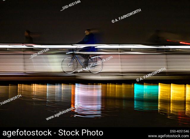 Copenhagen, Denmark A panning shot of a bicyclist crossing the Brygge Bridge, Bryggebroen, bicycle bridge in Sydhavn at night