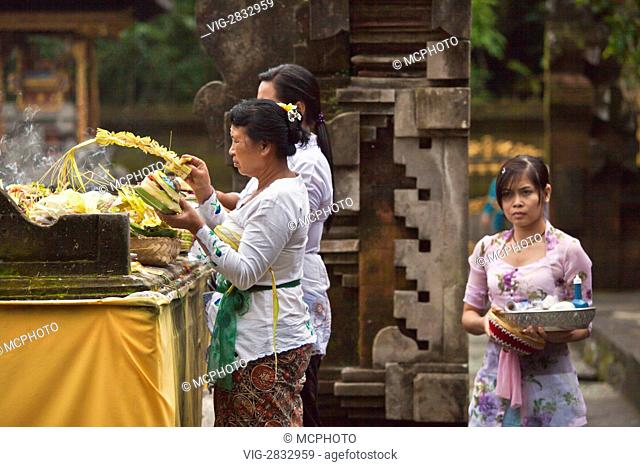 BALINESE WOMEN make offerings at PURA TIRTA EMPUL a Hindu Temple complex and cold springs with healing waters - TAMPAKSIRING, BALI, INDONESIA - 02/12/2010