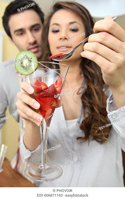 Couple eating strawberries from a glass