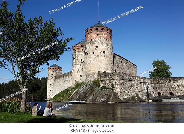 Girls relaxing beside Olavinlinna Medieval Castle St. Olaf's Castle, Savonlinna, Saimaa Lake District, Savonia, Finland, Scandinavia, Europe