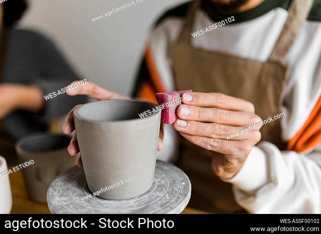 Craftsperson polishing clay container while working at workshop