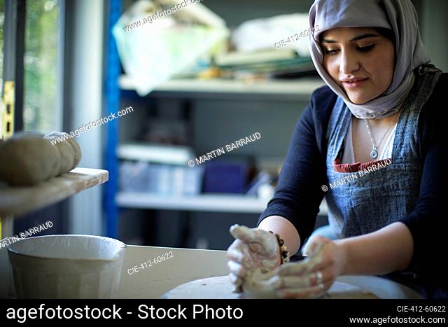 Young female Muslim artist at pottery wheel in art studio