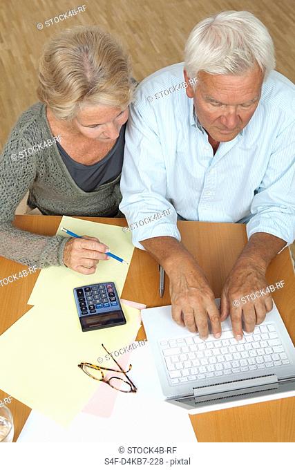 Senior couple using laptop and calculator