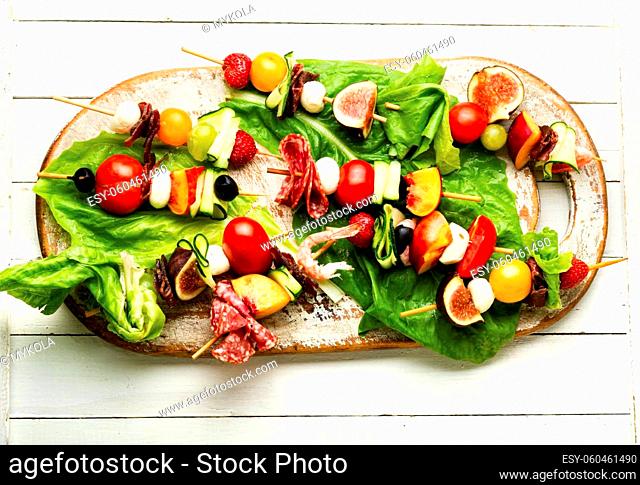appetizer of shrimps, jamon, fruits and vegetables on wooden skewers.Flat lay