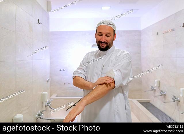 a portrait of a man in abdesthana using a towel after taking ablution