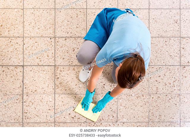 High Angle View Of Female Janitor Rubbing Floor With Rag