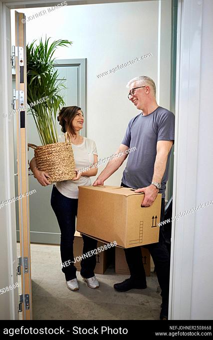 Mature couple carrying plant and cardboard box