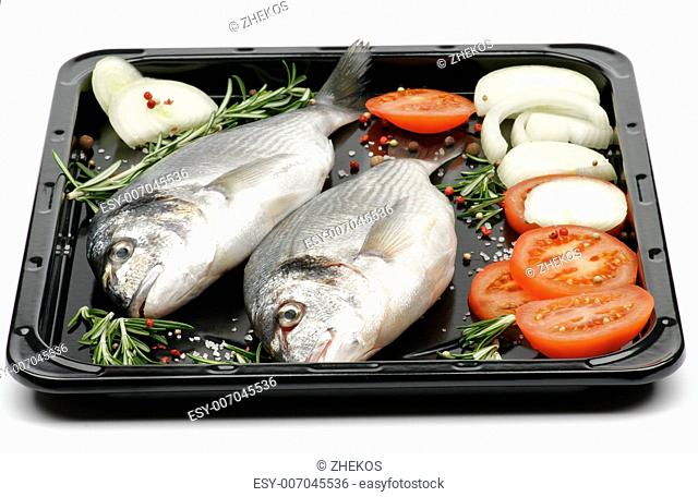 Preparing to FryingTwo Fresh Gilthead Fish with Onion, Tomatoes, Spices and Rosemary on Black Dripping Pan on white background
