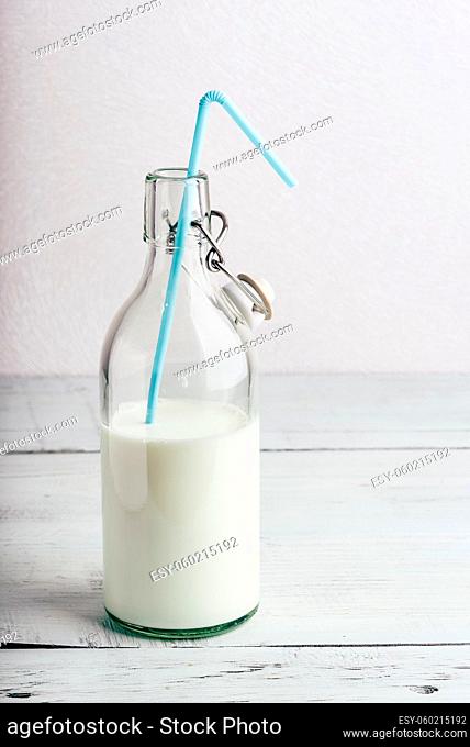 Glass bottle of milk with blue straw