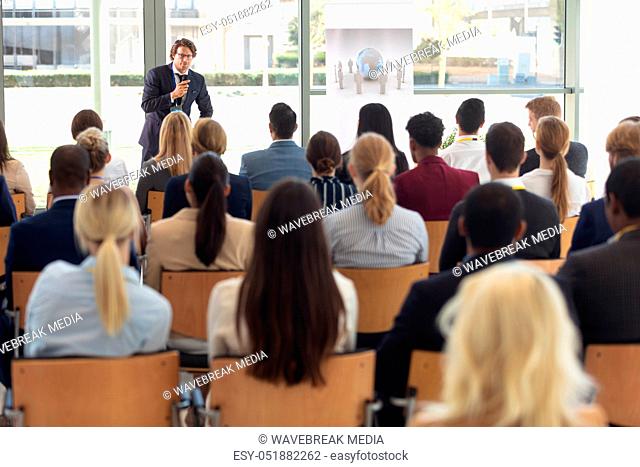 Mature Caucasian male executive doing speech in conference room, answering question